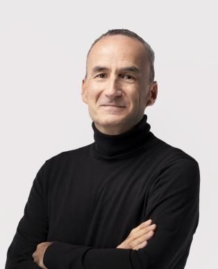 A man in a black polo neck with arms folded